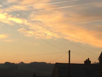 Low angle view of silhouette cables against sky during sunset