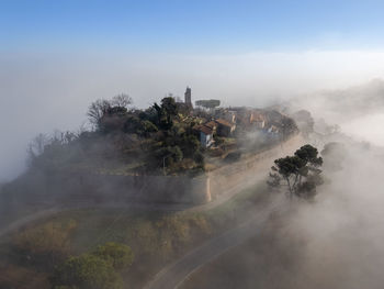 Aerial view of the medieval village of fiorenzuola di focara immersed in fog near pesaro e urbino