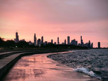 Scenic view of sea and buildings against sky during sunset