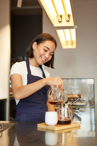 Portrait of smiling young woman having drink at home