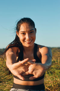 Portrait of smiling young woman on field against clear sky