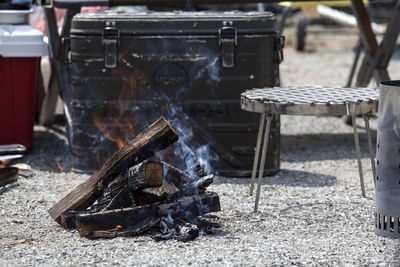 Burning firewood by barbecue grill on field during camping