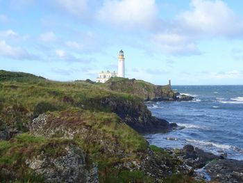 Lighthouse by sea against sky