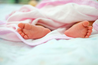 Low section of baby feet on bed