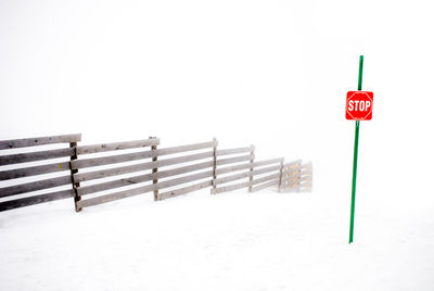 Sign board on snow covered land against clear sky