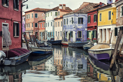 Boats moored in canal amidst buildings