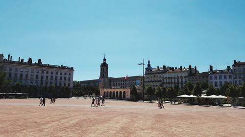 Town square by historic buildings against clear blue sky