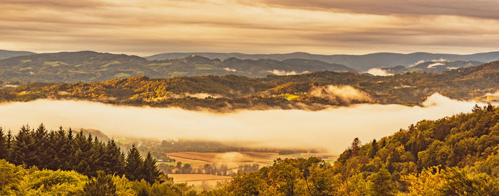 Scenic view of trees and mountains against sky during sunset