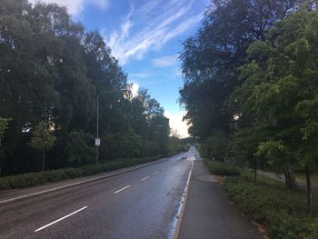 Road amidst trees against sky in city