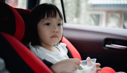 Portrait of cute baby girl sitting in container
