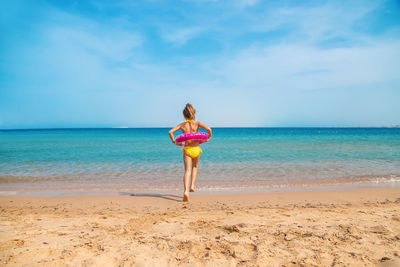 Rear view of girl running towards water on beach