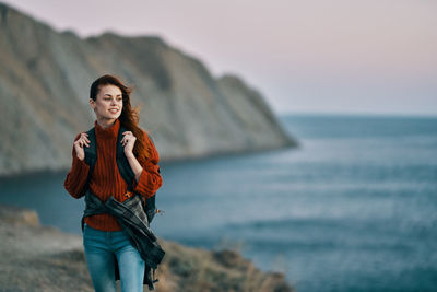 Portrait of young woman standing in sea against sky