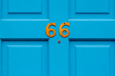 House number 66 on a blue wooden front door in london 