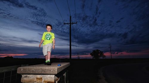 Full length of boy standing on surrounding wall