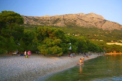 People on shore against mountain range