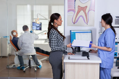 Side view of woman using digital tablet while standing in office