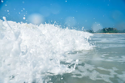 Waves splashing on shore against clear sky