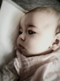 Close-up portrait of cute baby relaxing on bed