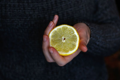 Female hand holding one yellow slice lemon fruit. hand holds lemon slice on white background. 