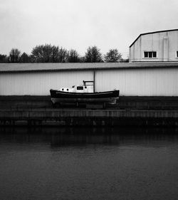 Boat on lake by building against sky