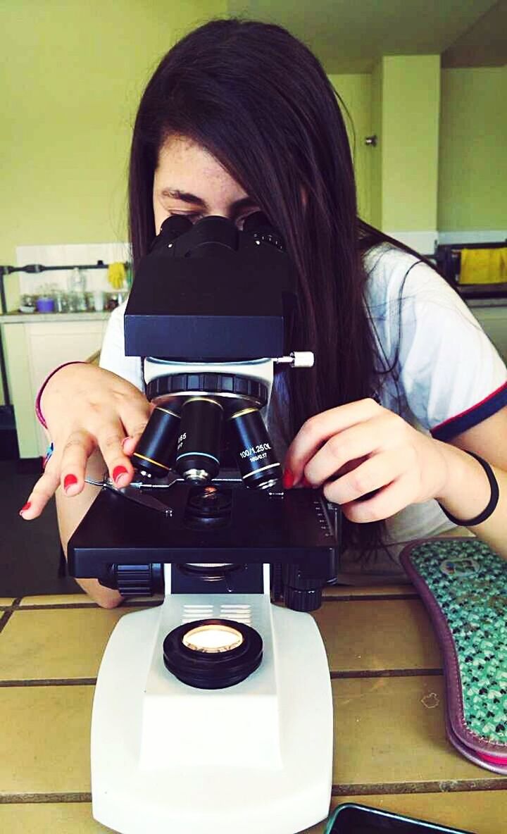 YOUNG WOMAN USING MOBILE PHONE IN KITCHEN