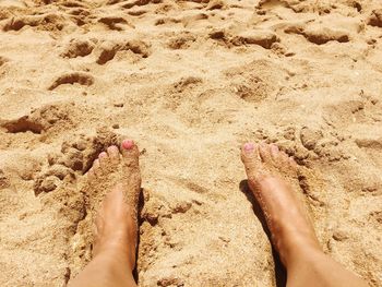 Low section of woman legs on sand at beach