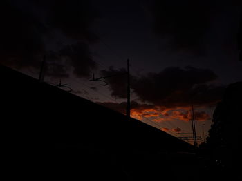 Low angle view of silhouette electricity pylon against sky at sunset