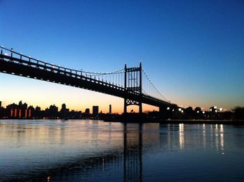 Suspension bridge over river at sunset