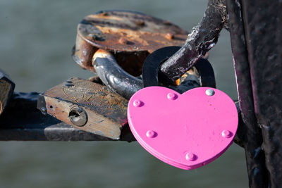 Pink heart-shaped padlock attached to bridge, close up