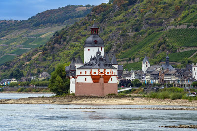 Scenic view of river by buildings against mountain