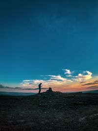 Silhouette man standing on shore against sky during sunset