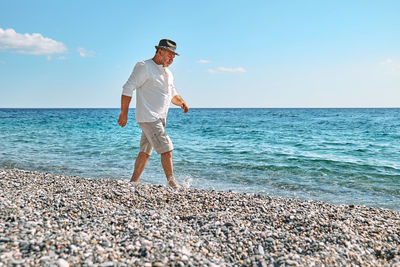 Happy middle-aged bearded man walking along beach. concept of leisure activities, wellness, freedom