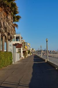 Street amidst buildings against clear blue sky