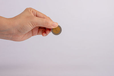 Cropped image of hand holding camera against white background