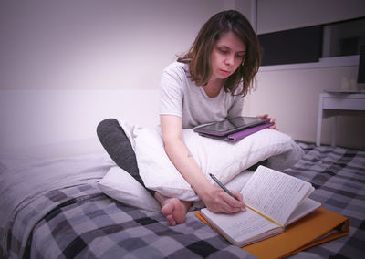 Young woman sitting on book at home