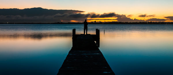 Pier over lake against sky during sunset