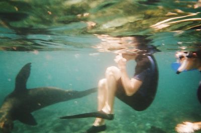 Reflection of man swimming in fish underwater