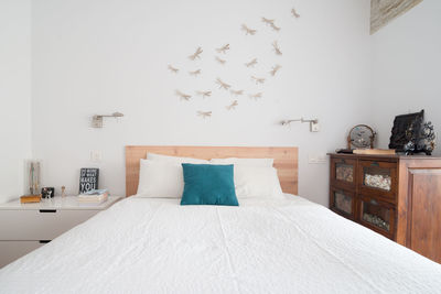 Cozy bedroom in white with dragonflies and wooden headboard