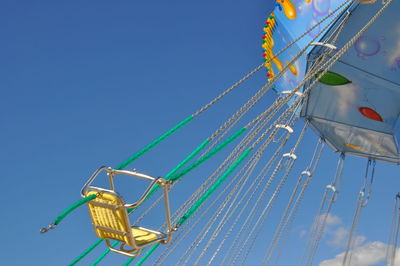 Low angle view of empty chain swing ride against sky