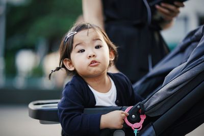 Portrait of cute toddler girl sitting in baby stroller