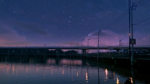 Bridge over lake against sky at night