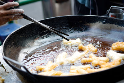 Close-up of person preparing food in cooking pan