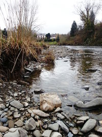 River flowing through rocks against sky