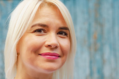 Portrait of middle-aged beautiful cheerful woman on wooden wall background. success, antiaging