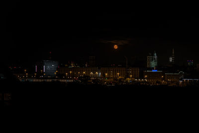 Illuminated buildings against clear sky at night