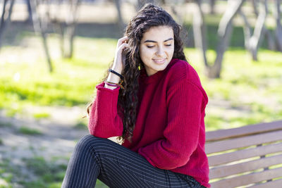 Smiling teenage girl sitting on bench in park