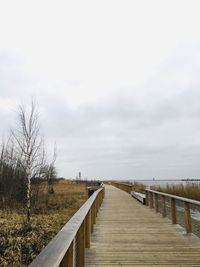 View of wooden boardwalk leading towards sky
