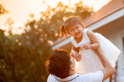 Father carrying daughter against tree