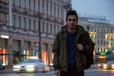 Portrait of young man standing on street in city