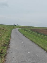 Road amidst field against sky